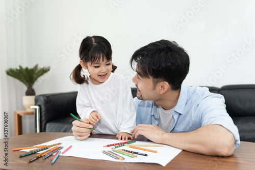 A pair of young Asian father and daughter are drawing in the living room
