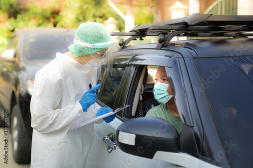 Doctor or nurse wearing PPE, N95 mask, face shield  and personal protective gown standing beside the car/road screening for Covid-19 virus 
