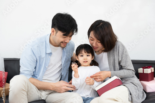 Young Asian mom and dad are unpacking gifts with their daughter