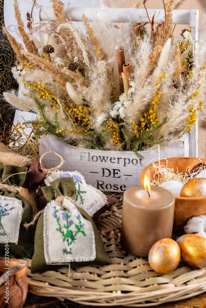 Fototapeta premium On the table there is still life of dried flowers, a sweet table for the holiday. Easter decoration and colored eggs. Easter holiday concept.