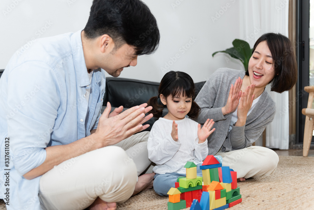 Young Asian mom and dad are building blocks with their daughter