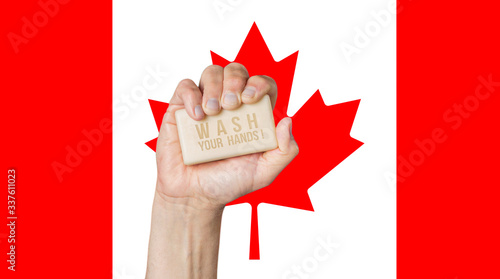 Male hand holding soap with words: Wash Your Hands, against a Canadian flag photo