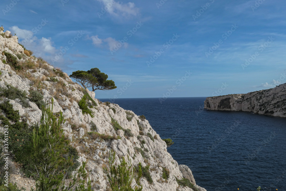 Mountains with green grass and grey rocks near the sea. Blue sky and white clouds. Mountains with green grass and grey rocks near the sea. Blue sky and white clouds.