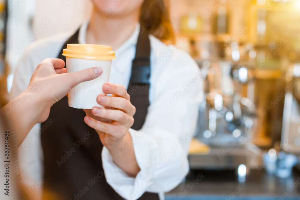 Closeup female hands are holding paper disposable cup of coffee. Woman prepared, brewed espresso, americano, latte cappuccino in cafe. Barista is giving order to client. Take away, to go concept. Closeup female hands are holding paper disposable cup of coffee. Woman prepared, brewed espresso, americano, latte cappuccino in cafe. Barista is giving order to client. Take away, to go concept.