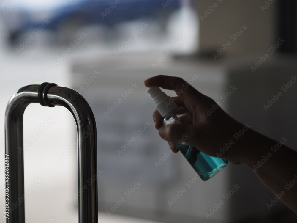 Women pressing alcohol spray to stainless steel handle door clean and