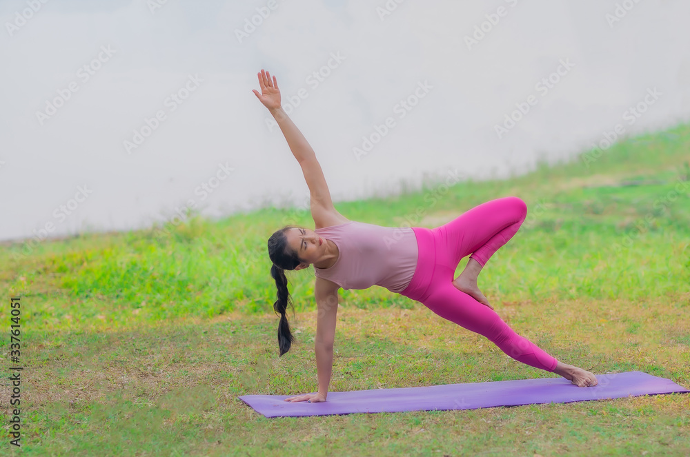 Fototapeta premium Strong women practice difficult yoga postures by the lake.