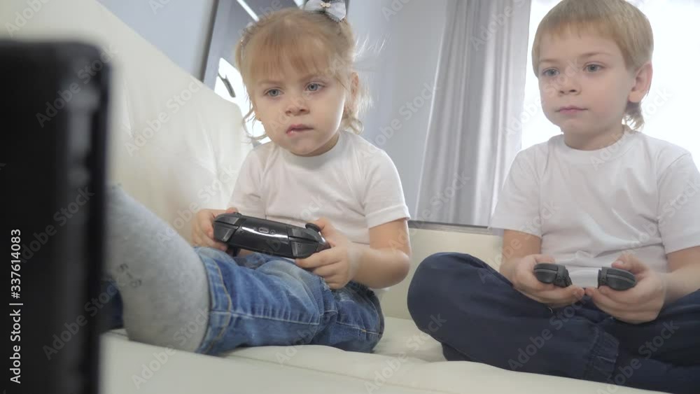 children play console lifestyle in gamepads teamwork. kids a boy and a girl are playing a portable set-top box in a TV controller. happy family little boy and girl have fun online games children play console lifestyle in gamepads teamwork. kids a boy and a girl are playing a portable set-top box in a TV controller. happy family little boy and girl have fun online games