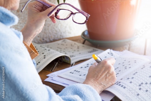 senior woman doing crossword puzzles or hobbies with glasses in hand photo