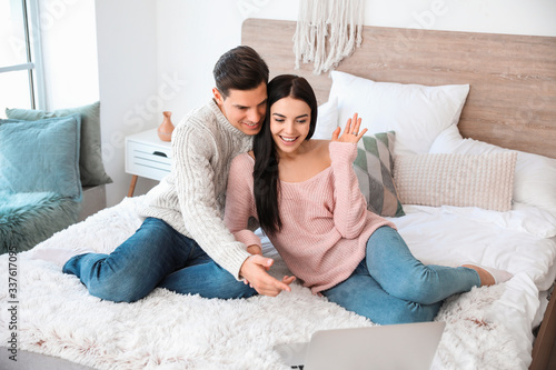 Happy young couple with lap...