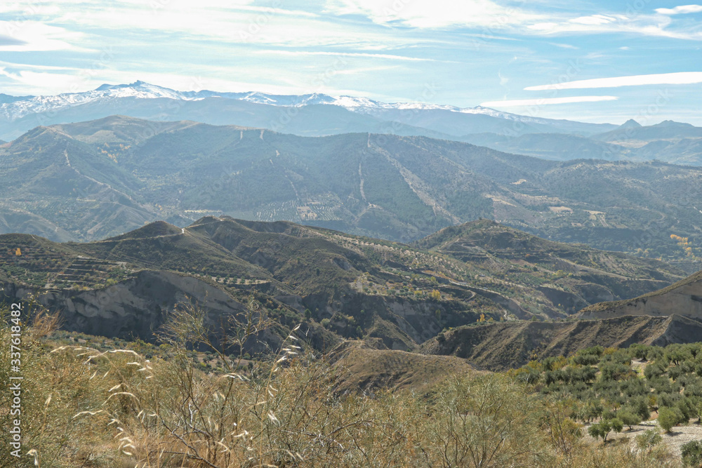 Mountains with snow on the top. Green hills under the blue sky with white clouds. Mountains with snow on the top. Green hills under the blue sky with white clouds.
