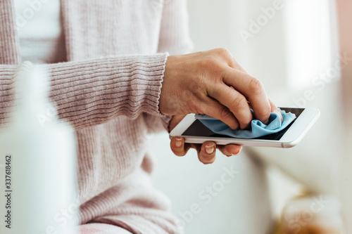 Tableau sur toile Close-up of woman cleaning mobile phone with fabric cloth.