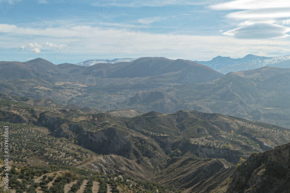 Naklejka premium Mountains with snow on the top. Green hills under the blue sky with white clouds.
