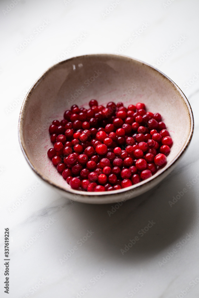 lingonberry berries in white bowl on marble table lingonberry berries in white bowl on marble table