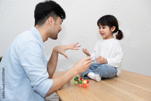 A pair of young Asian father and daughter are applying nail polish in the living room