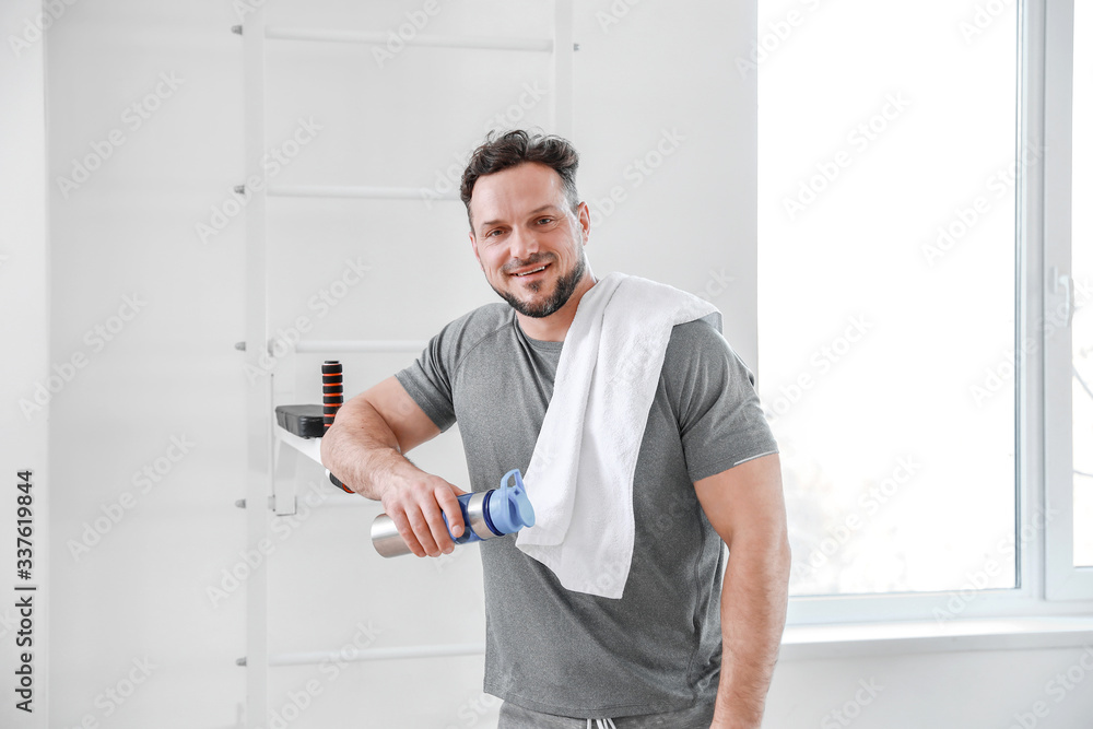Sporty man with bottle of water in gym