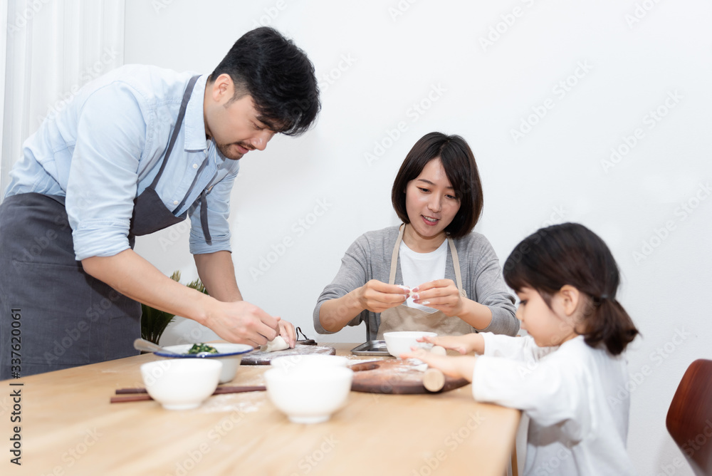 Young Asian mom and dad making dumplings with daughter Young Asian mom and dad making dumplings with daughter