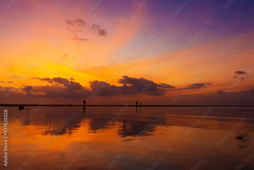 Burning bright sky during sunset on a tropical beach. Sunset during the exodus, the strength of people walking on water