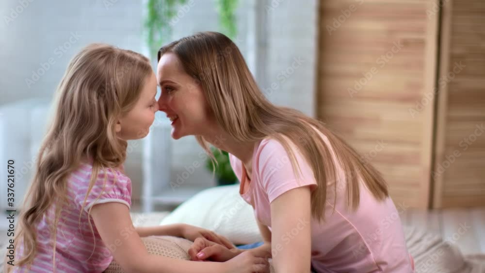 Happy young mother and cute daughter playing together touching nose. Medium shot on RED camera Happy young mother and cute daughter playing together touching nose. Medium shot on RED camera