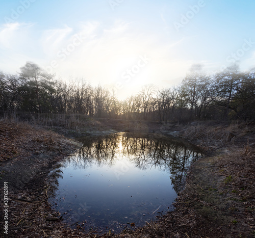 small quiet lake in a forest at the sunset