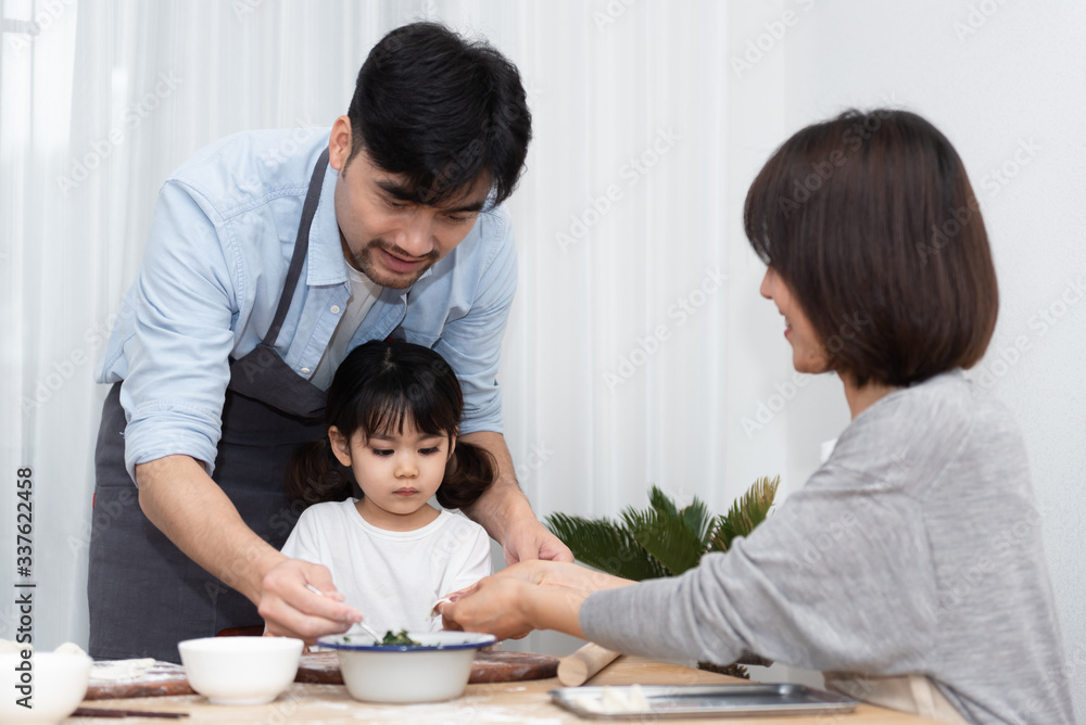 Young Asian mom and dad making dumplings with daughter Young Asian mom and dad making dumplings with daughter