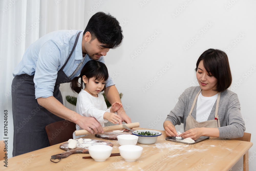 Young Asian mom and dad making dumplings with daughter Young Asian mom and dad making dumplings with daughter