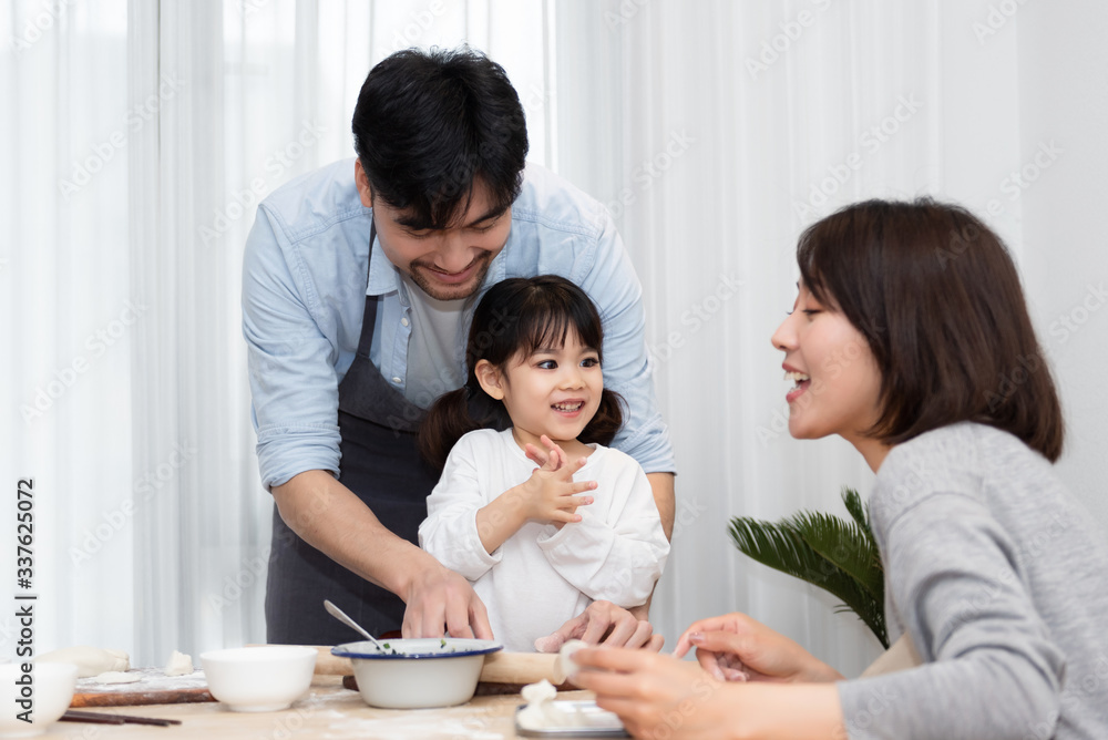 Young Asian mom and dad making dumplings with daughter Young Asian mom and dad making dumplings with daughter