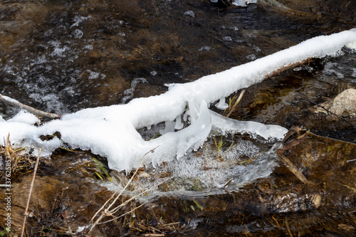 A melting or freezing stream in late autumn or early spring on a sunny day. Seasonal changes in nature. photo