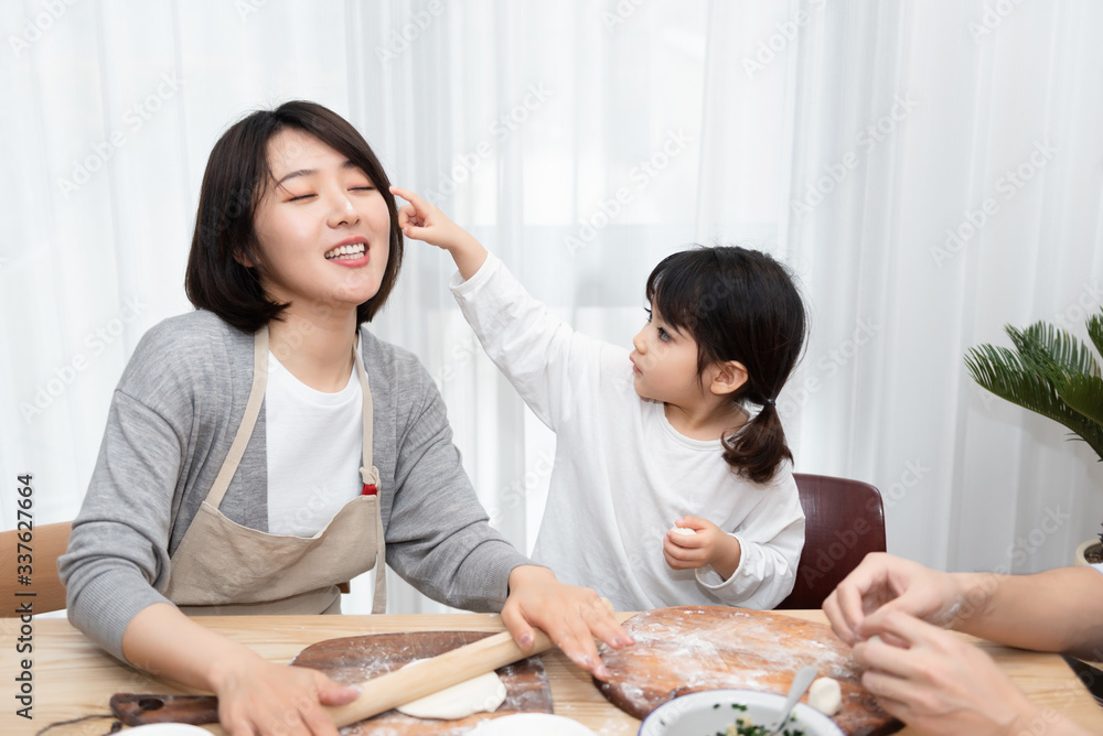 Young Asian mom and dad making dumplings with daughter Young Asian mom and dad making dumplings with daughter