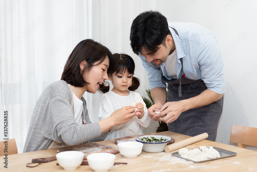 Young Asian mom and dad making dumplings with daughter Young Asian mom and dad making dumplings with daughter