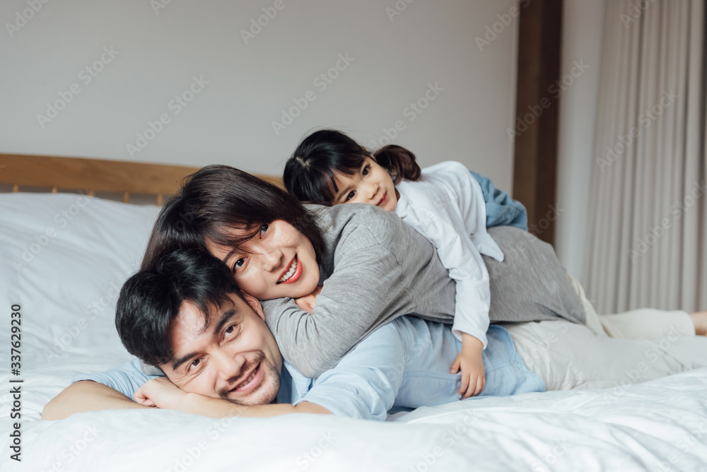 Young Asian father and mother are playing with their daughter on the bed Young Asian father and mother are playing with their daughter on the bed