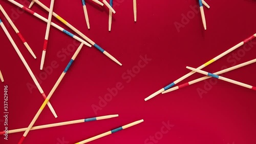 Top View of Mikado pick-up sticks falling on red surface, Slow Motion