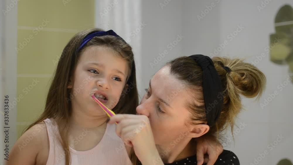 Young mother brushes her teeth to her daughter child Young mother brushes her teeth to her daughter child