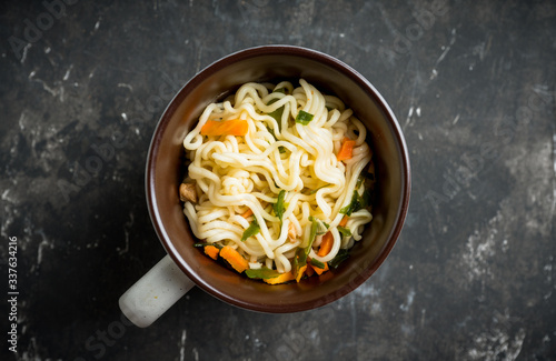 Instant noodles in cup on the rustic background. Selective focus. Shallow depth of field. 