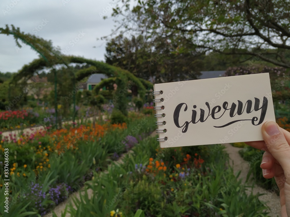 The beautiful garden filled with different colorful Spring flowers at Claude Monet's Giverny home outside of Paris. View with calligraphic inscription 