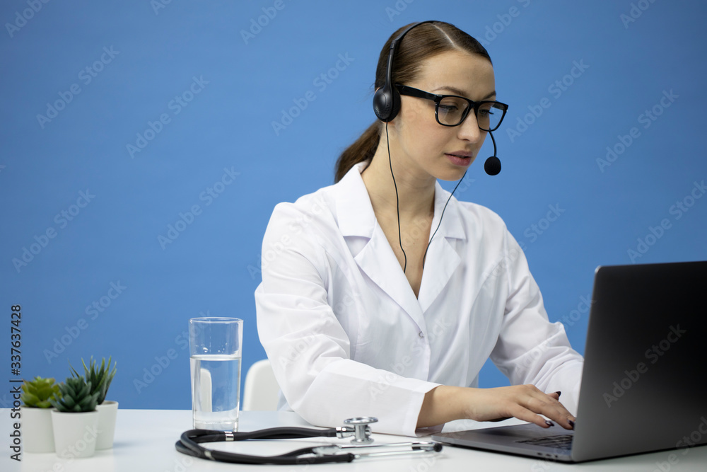 Online medical consultation service. Attractive female doctor in headset and white coat talking with patient by laptop. Diagnostics application for treatment advice. Technology and health care concept Online medical consultation service. Attractive female doctor in headset and white coat talking with patient by laptop. Diagnostics application for treatment advice. Technology and health care concept