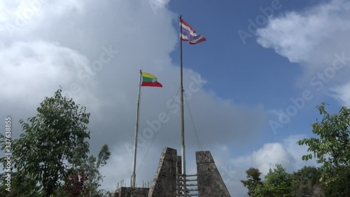 Flags of Thailand and Myanmar standing together as a mark of territory boarder between two country, in strong wind and cloudy day.
