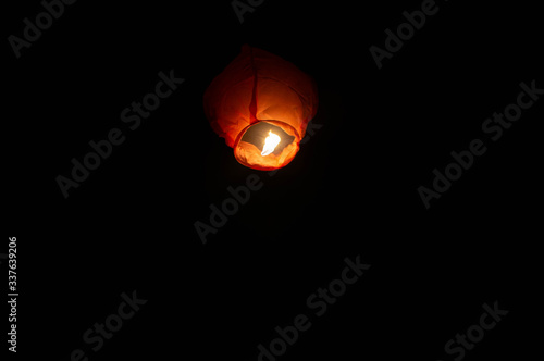 A red coloured sky lantern with the flames showing clearly lifiting off