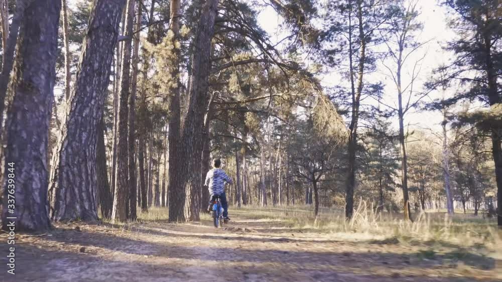 Funny boy cyclist rides in the sunny forest on a mountain bike. Adventure travel. Funny boy cyclist rides in the sunny forest on a mountain bike. Adventure travel.