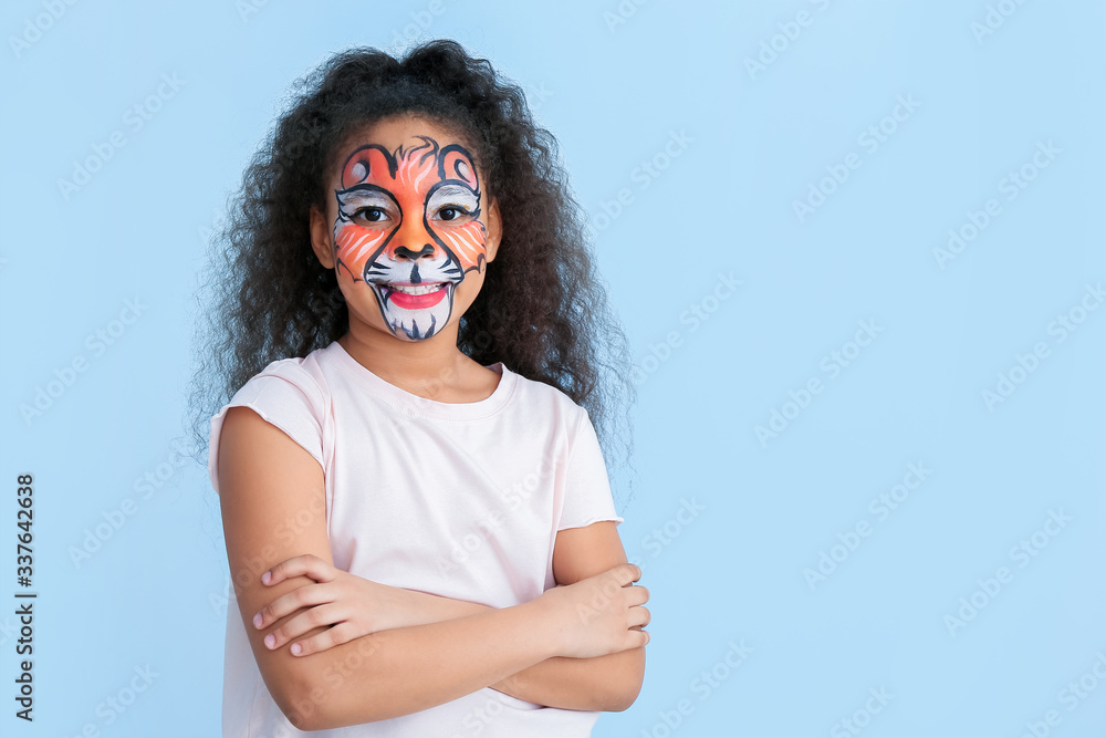 Funny African-American girl with face painting on color background Funny African-American girl with face painting on color background