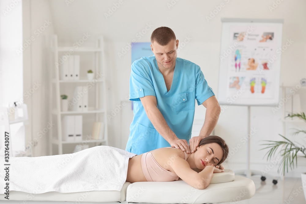 Massage therapist working with female patient in medical center