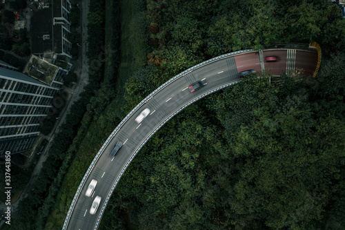Aerial drone overhead shot of curving highway road among trees to traffic tunnel through mountain in Chongqing, China