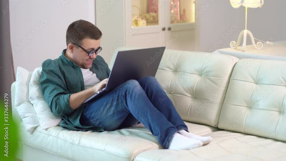 freak man with glasses is typing on laptop on sofa freak man with glasses is typing on laptop on sofa