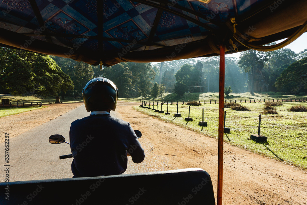 Fototapeta premium Angkor Wat Tuk Tuk ride - Small circuit tour. Sightseeing with a guide on a motorbike. Morning sunrise temple watching and driving all around. Siem Reap Cambodia vacations attractions.