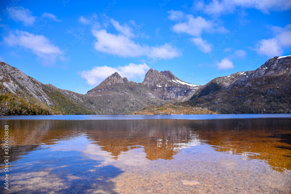 The grass field with lake, snow mountain and cloudy blue sky background in Tasmania, Australia