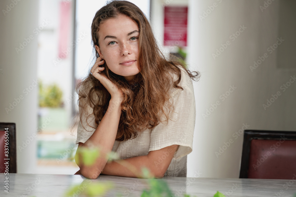 Beautiful young happy woman with long curly hair and a beautiful smile in a white T-shirt, portrait. At the hotel reception Beautiful young happy woman with long curly hair and a beautiful smile in a white T-shirt, portrait. At the hotel reception