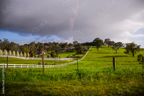 Tranquil rural landscape at sunset featuring an old wooden pile with cable and open green pasture under a cloudy sky