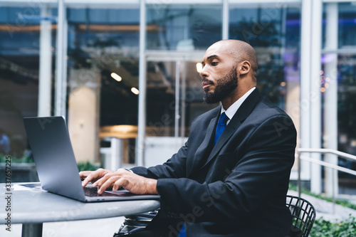 Focused male working on laptop near urban building