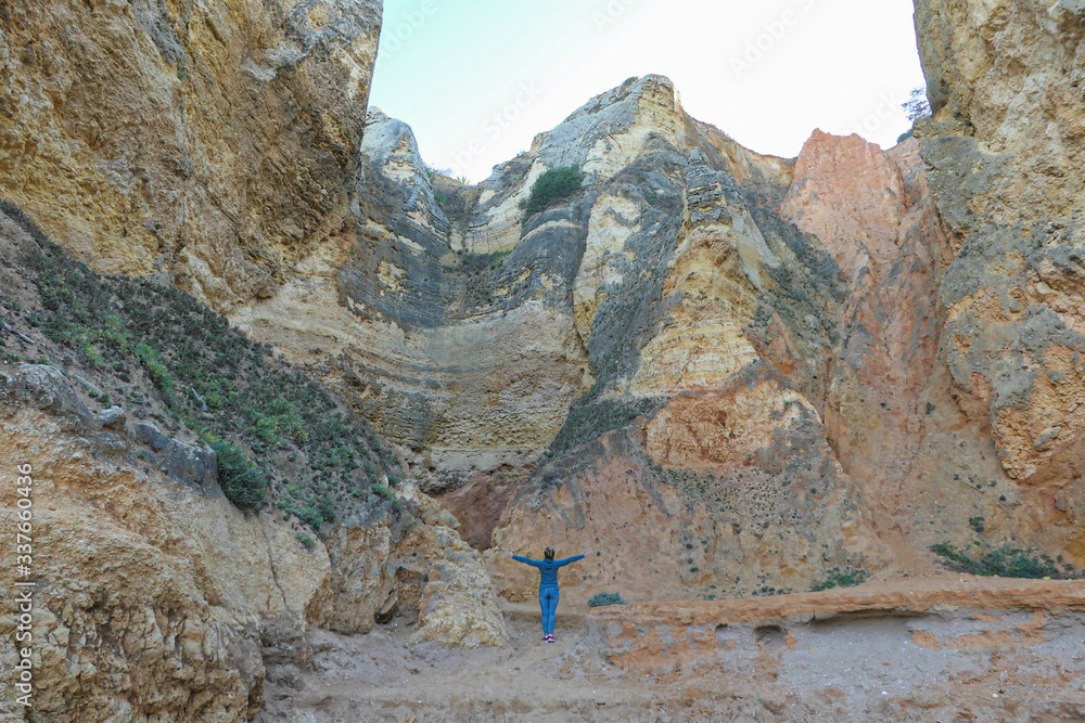 Girl in front of big and high colorful rocks.