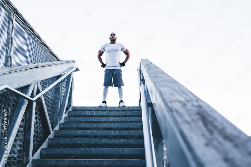 Muscular and strong black athlete standing at top of stairs