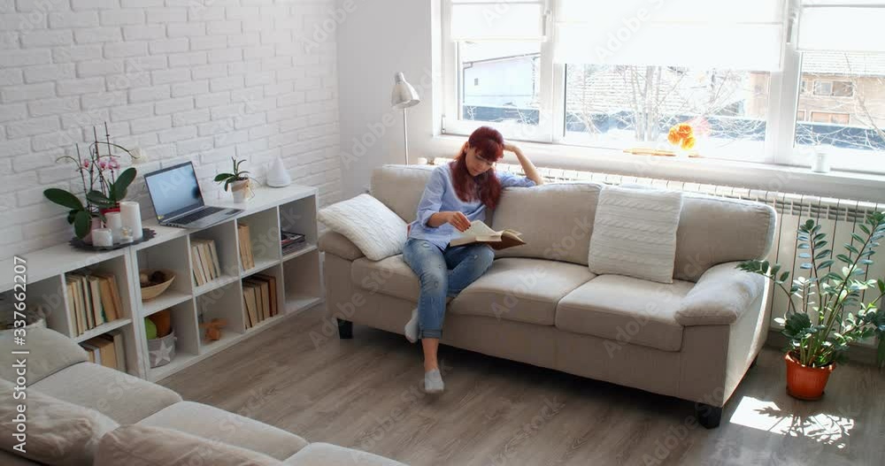 Stay at home during COVID-19. A woman sitting on a couch and reading a book, 4k Stay at home during COVID-19. A woman sitting on a couch and reading a book, 4k